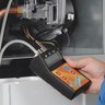 Ein Techniker hält ein Messgerät in der Hand, während er an einer Heizungsanlage arbeitet, um wichtige Daten zu erfassen.
